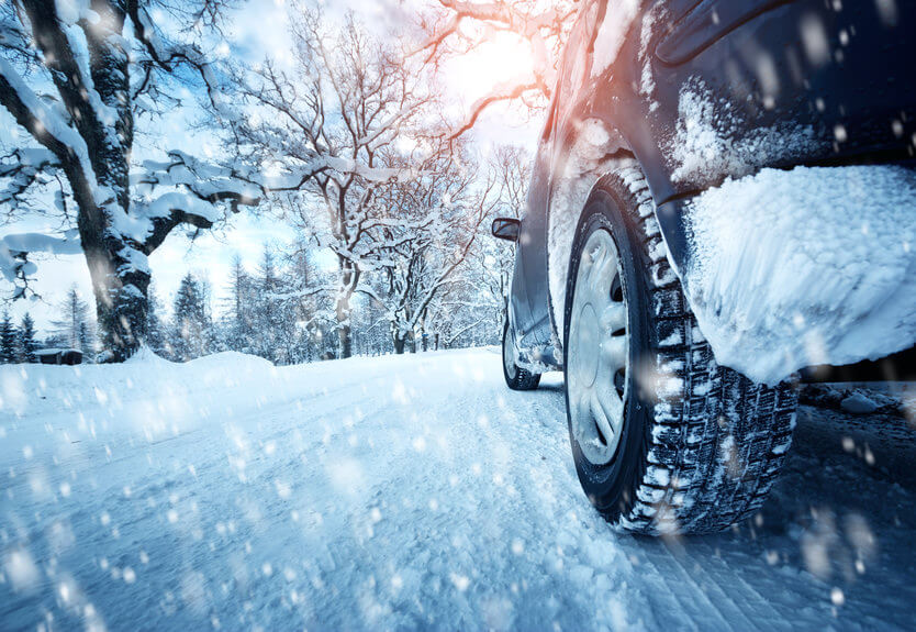 Car tires on winter road covered with snow. Vehicle on snowy alley in the morning at snowfall